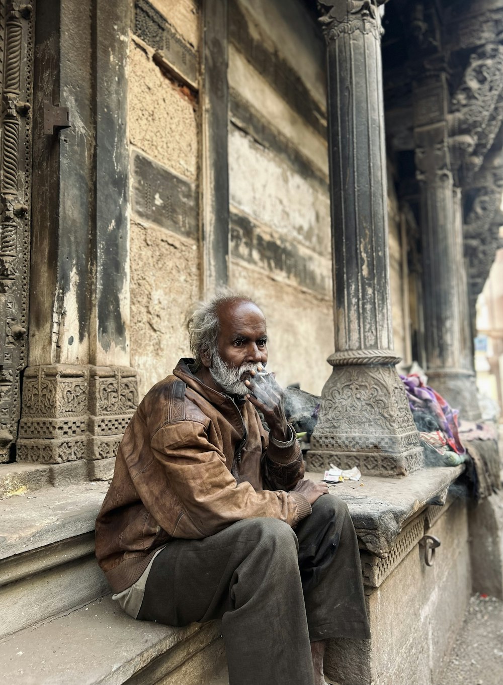 a man sitting on a ledge next to a pillar