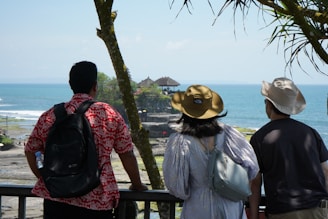 two men and a woman looking out at the ocean