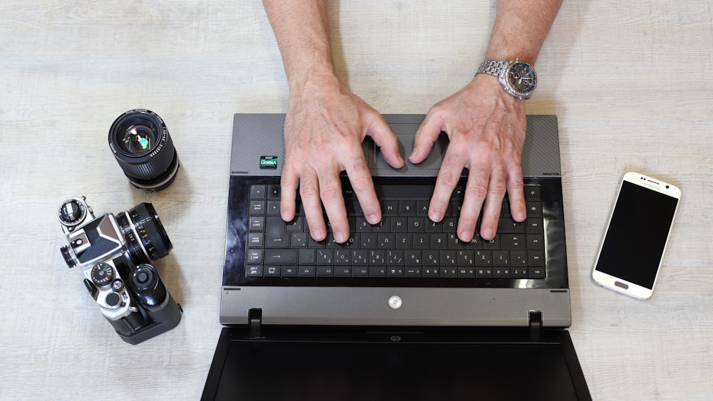 a person typing on a laptop with their hands on the keyboard