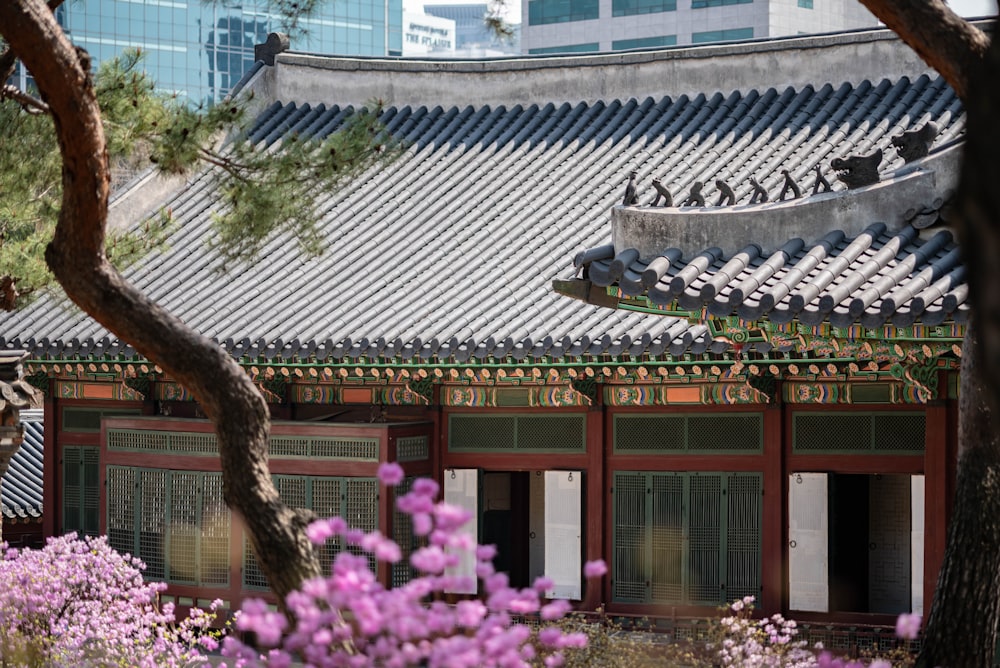 a building with a roof and a tree in front of it