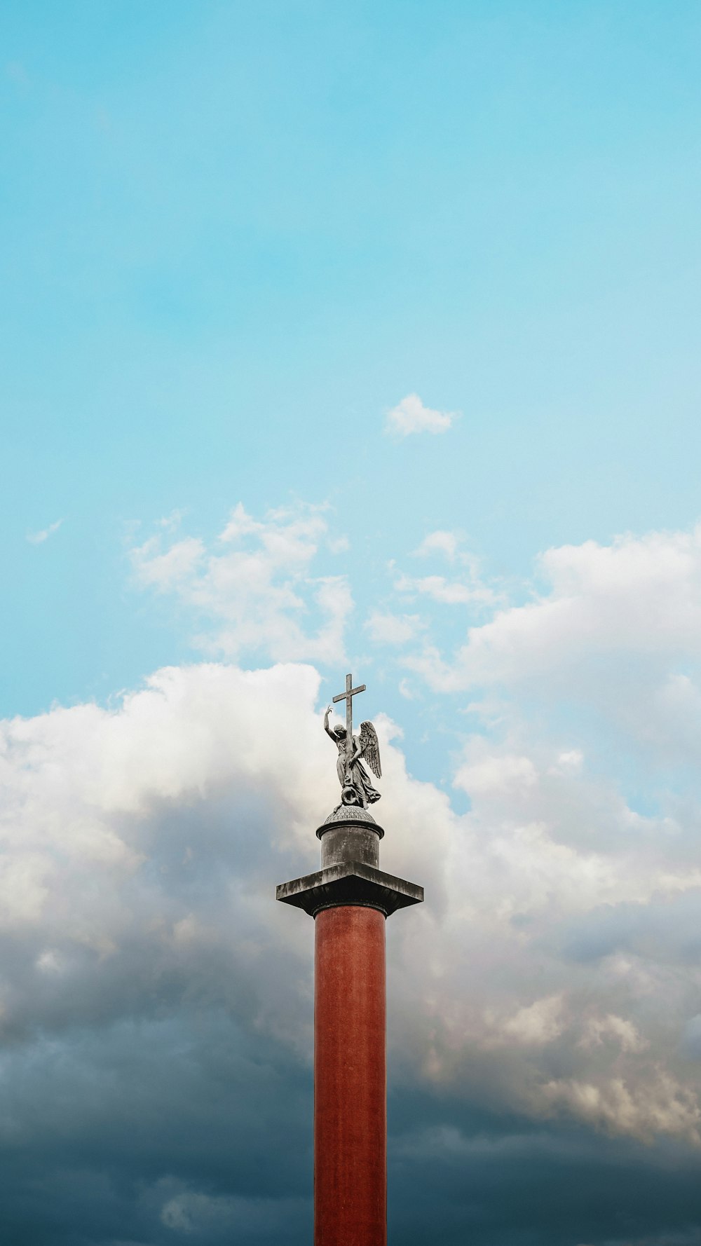 a statue on top of a tall red pillar