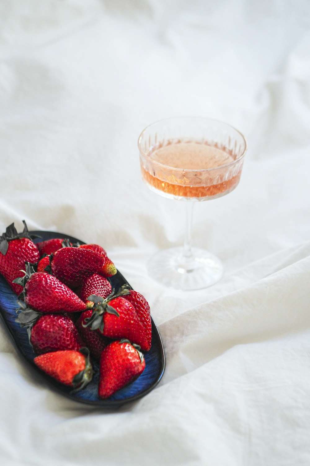 Ein Teller Erdbeeren neben einem Glas Wein