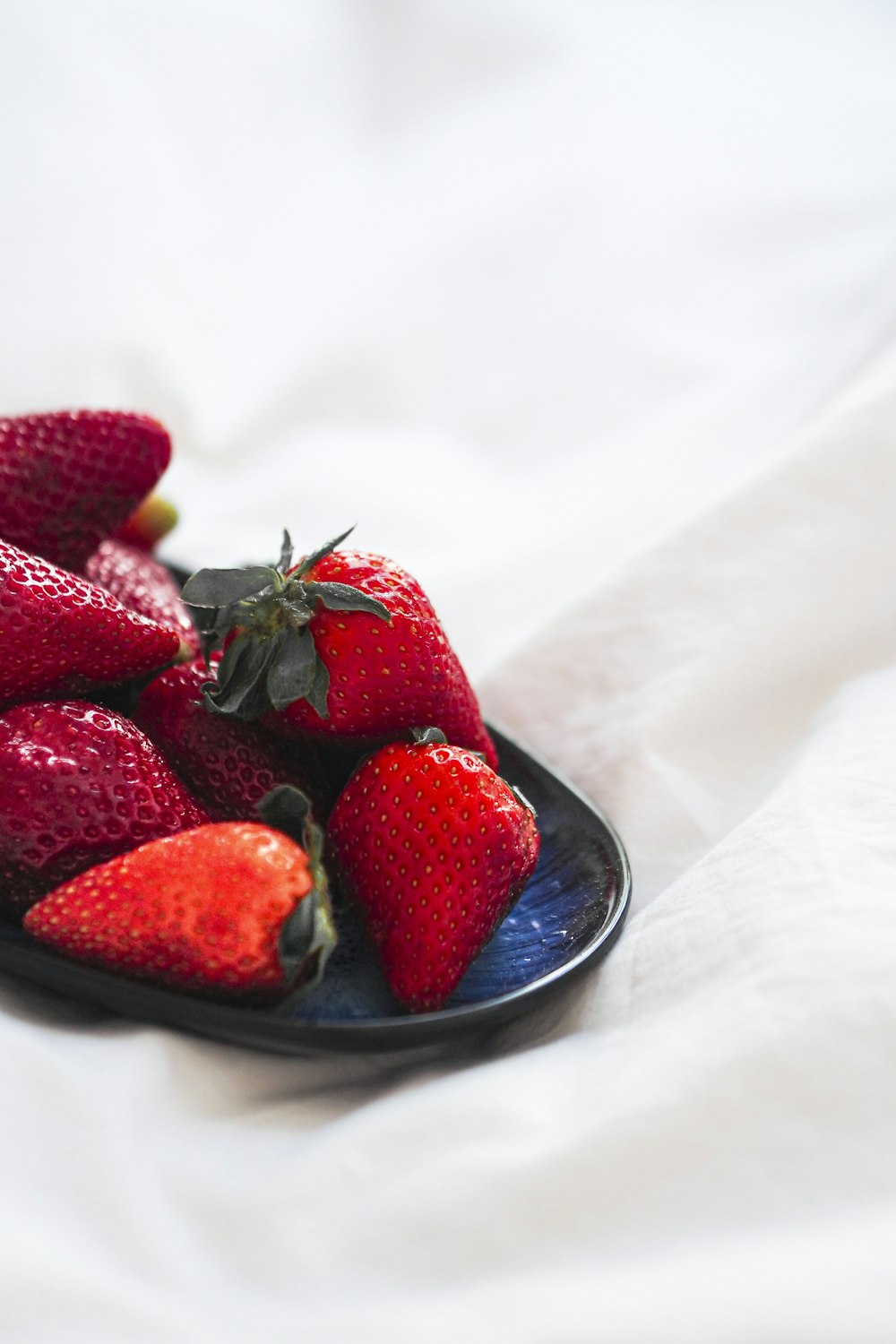 a plate of strawberries on a white sheet