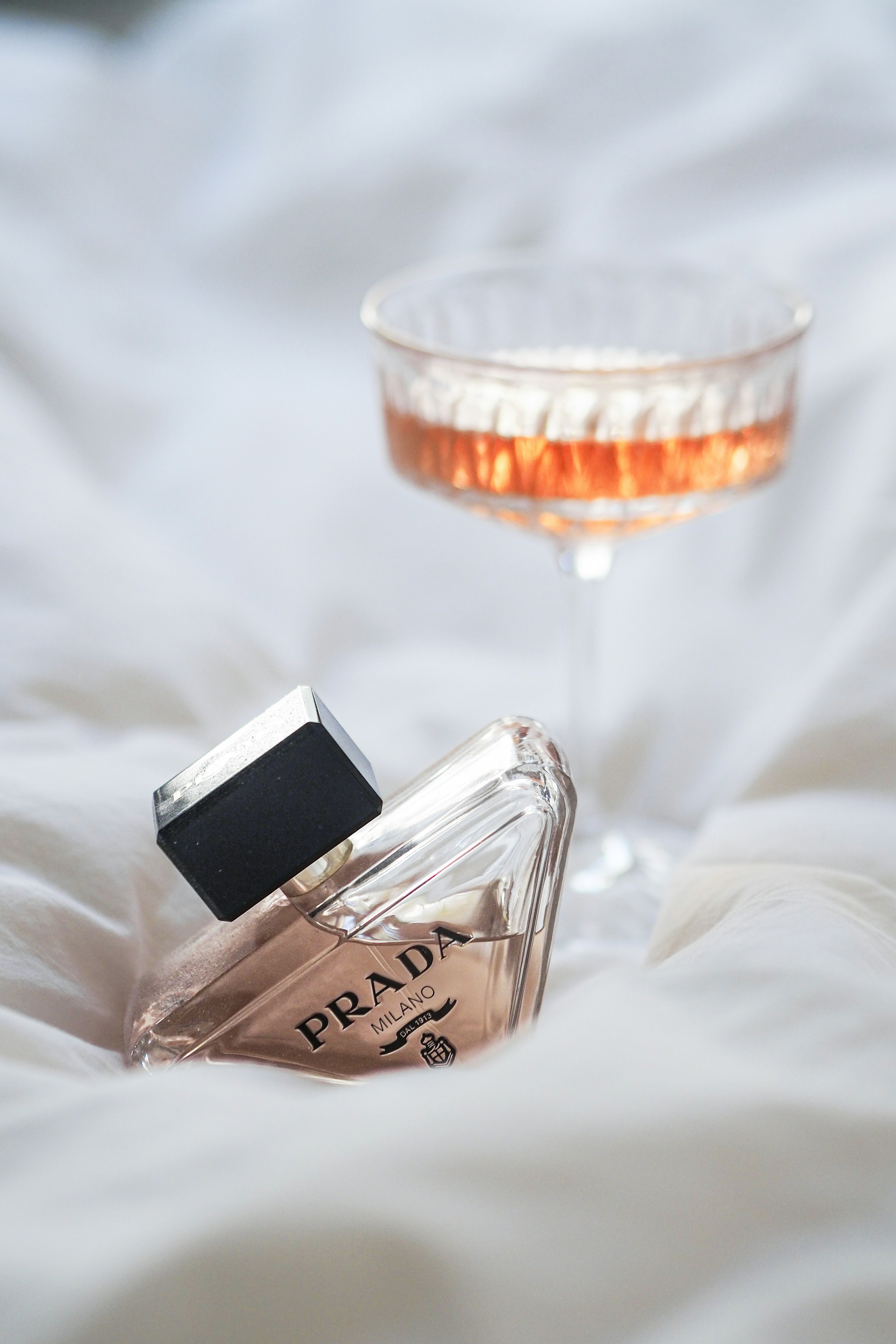 a bottle of perfume next to a glass of wine