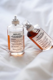 a bottle of replica and a bottle of deodorant on a bed