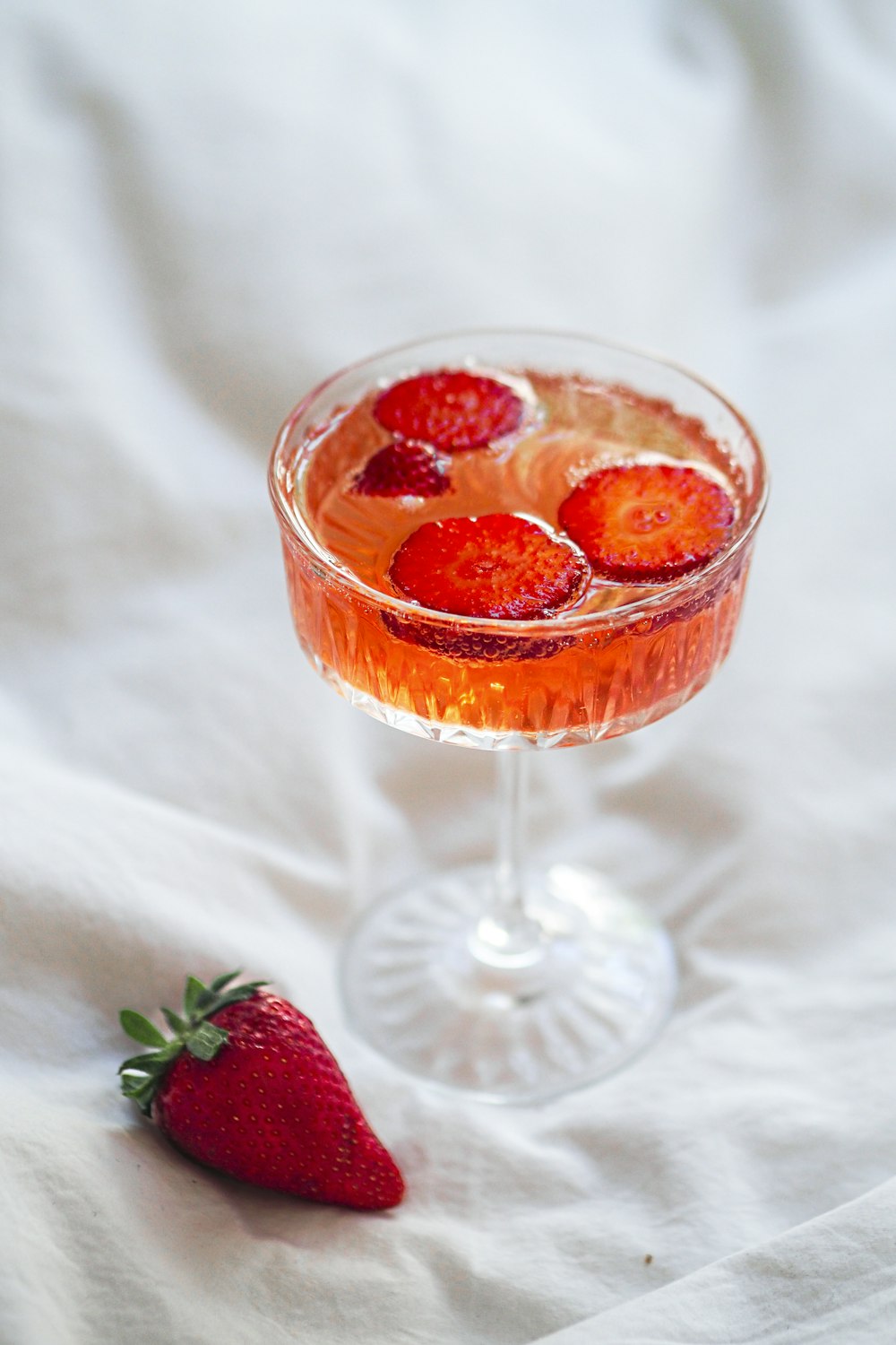 a glass filled with a drink and a strawberry on the side