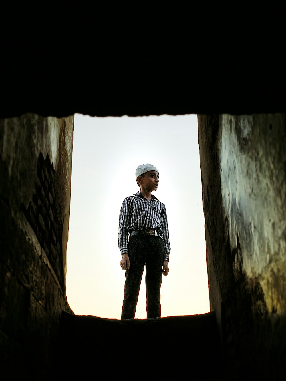 a man standing in a doorway with his hands in his pockets