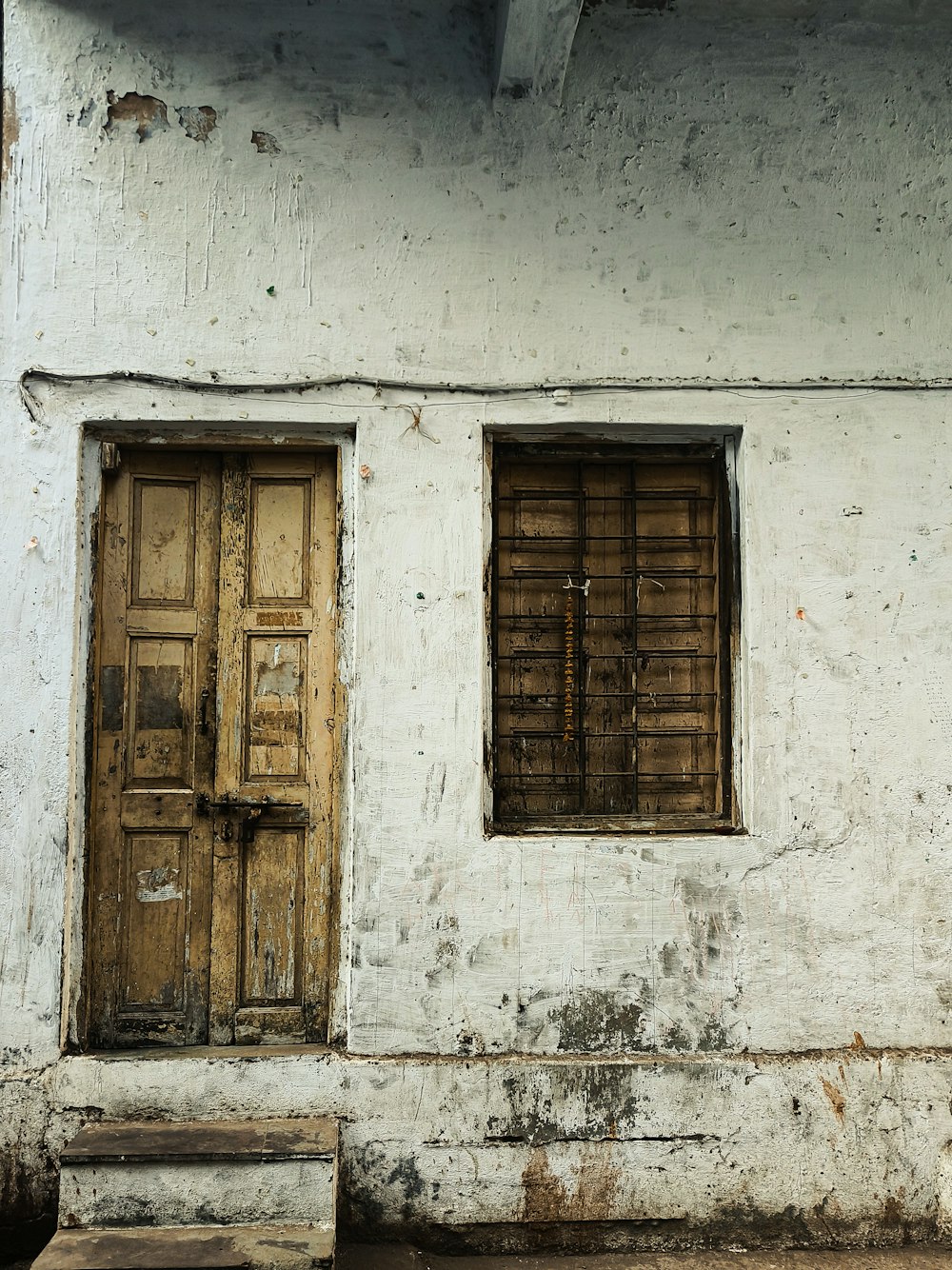 a white building with two wooden doors and a bench