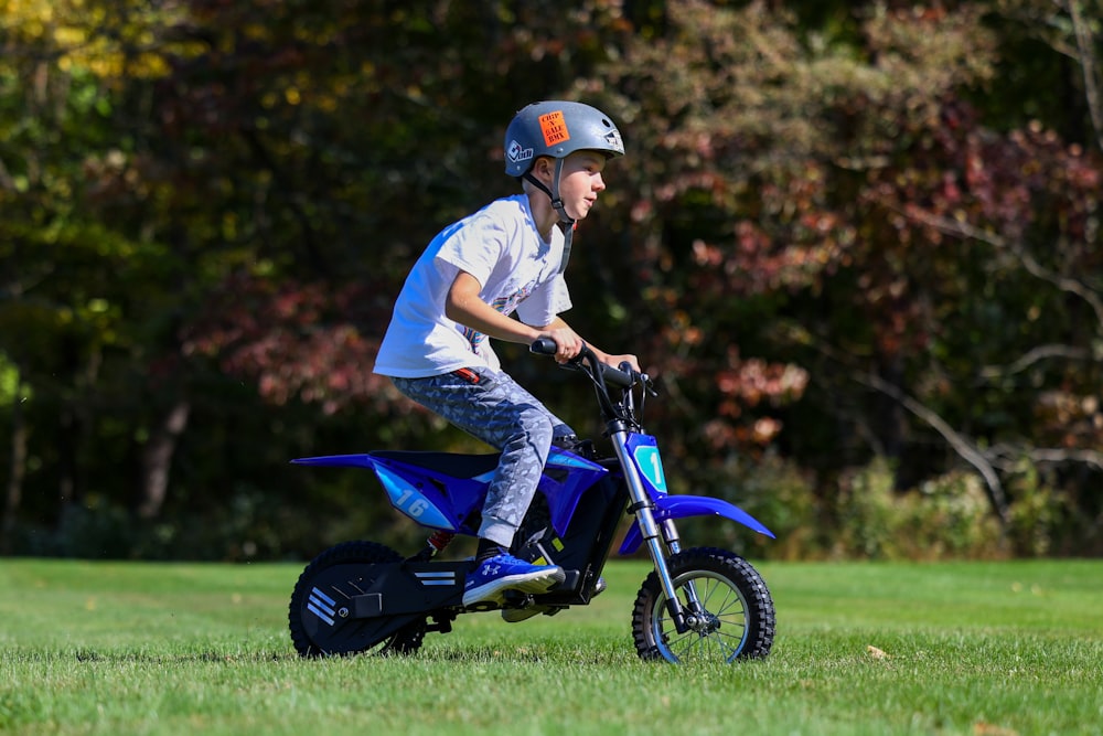 a young boy riding a small blue motorcycle