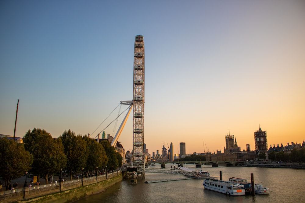 a ferris wheel sitting on top of a river next to a tall building