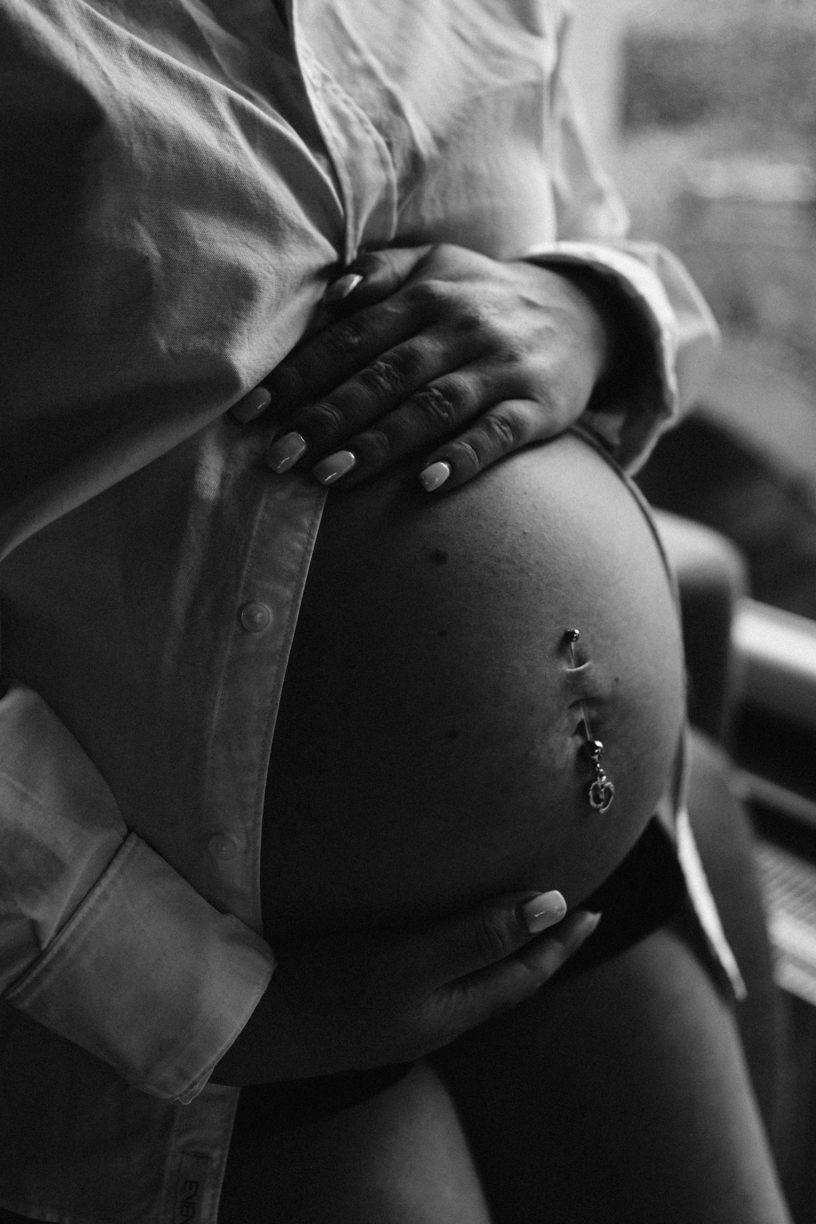 Detalle en blanco y negro de unas manos sobre una barriga de embarazo