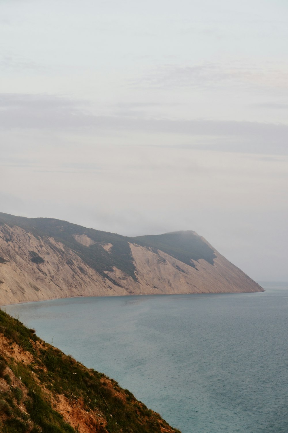 a man riding a horse down a hill next to a body of water