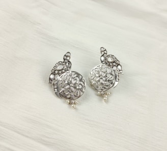 a pair of silver colored earrings on a white background