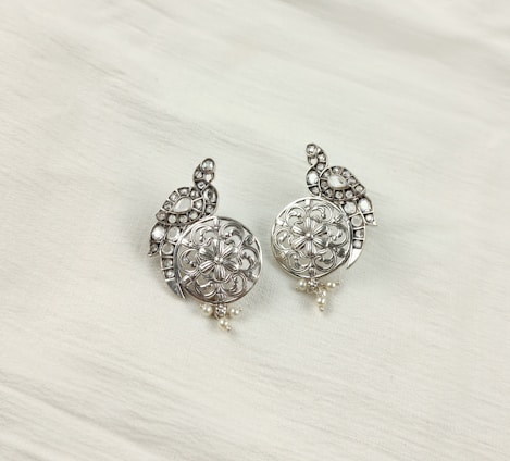 a pair of silver colored earrings on a white background