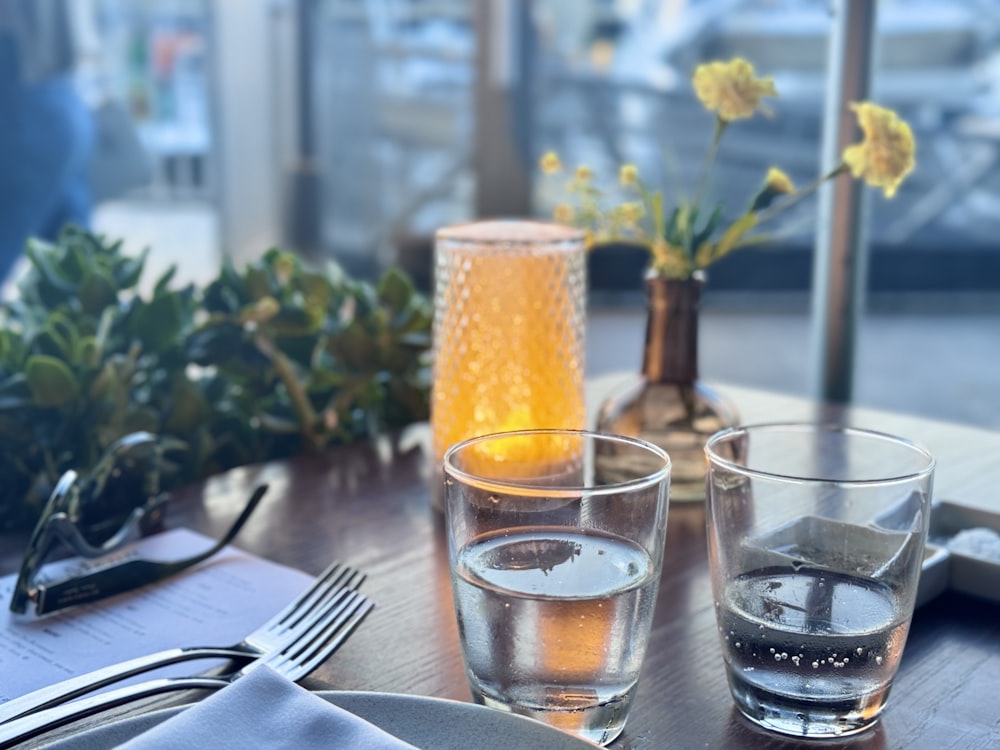 a wooden table topped with glasses and plates