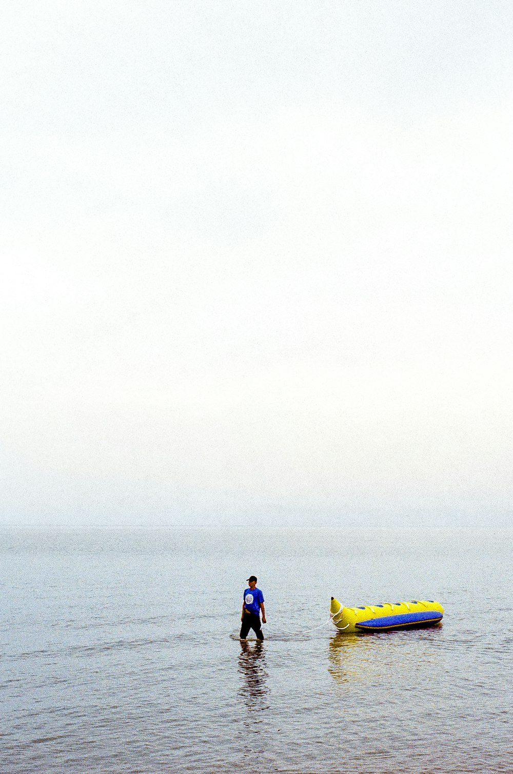 a man standing in the water next to an inflatable boat