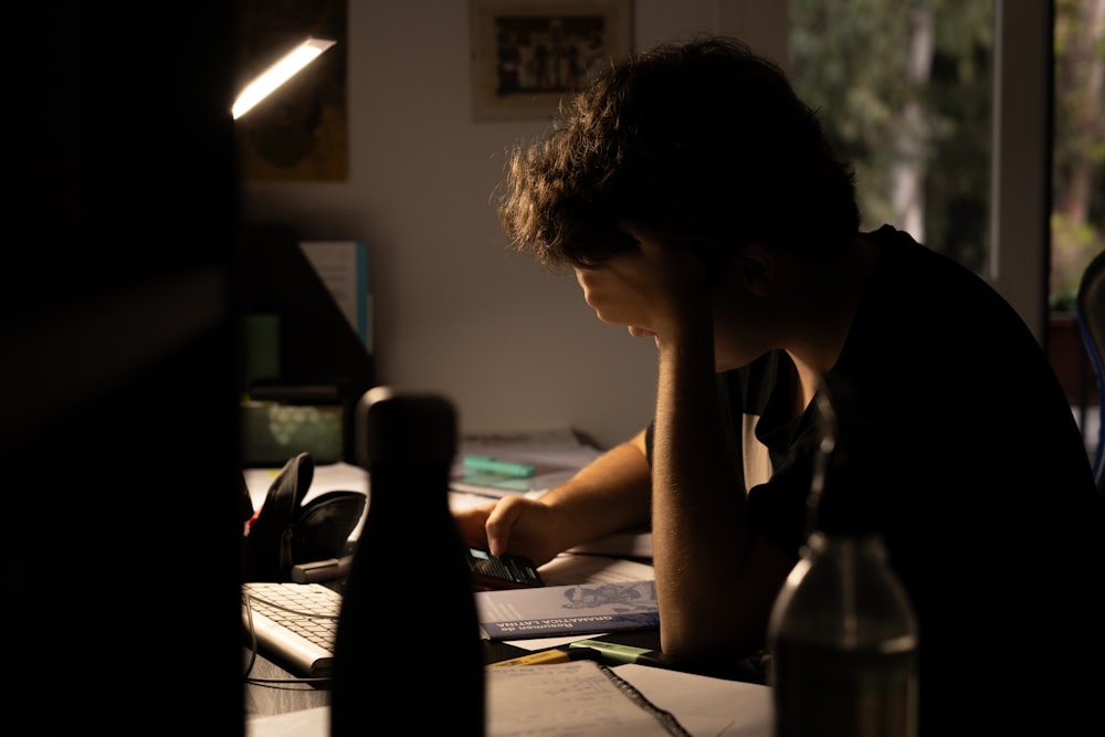 a man sitting at a desk working on a laptop computer