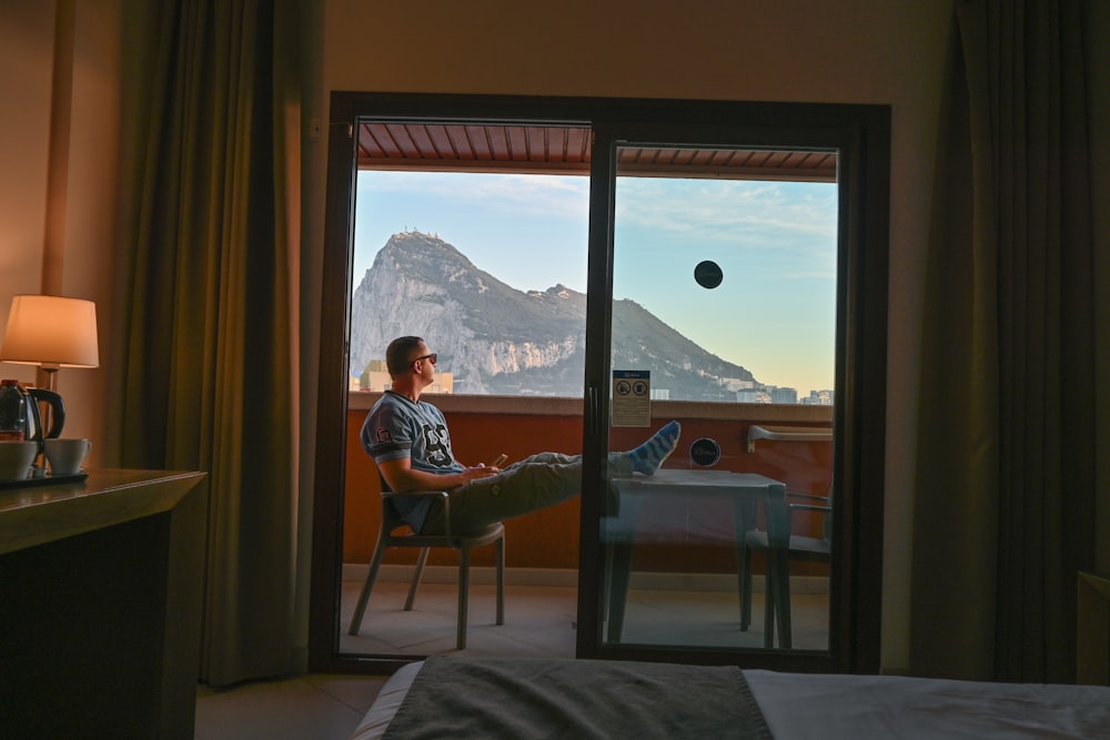 a man sitting in a chair looking out a window