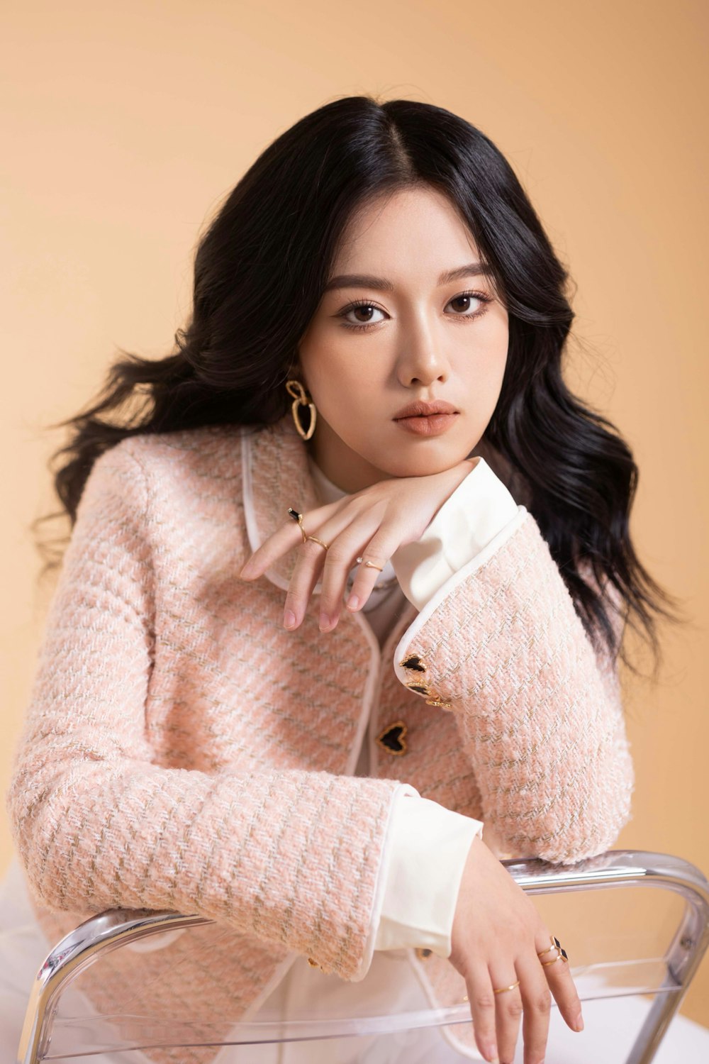 a woman sitting on top of a chair wearing a pink sweater