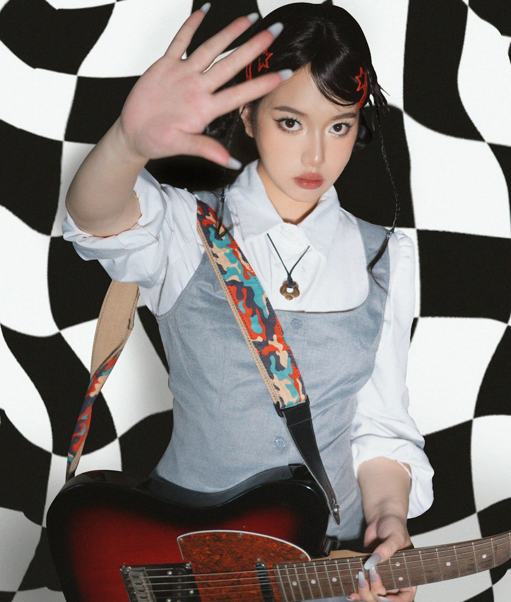 a woman holding a guitar in front of a black and white wall