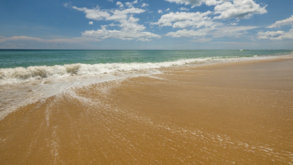 a sandy beach with waves coming in to shore