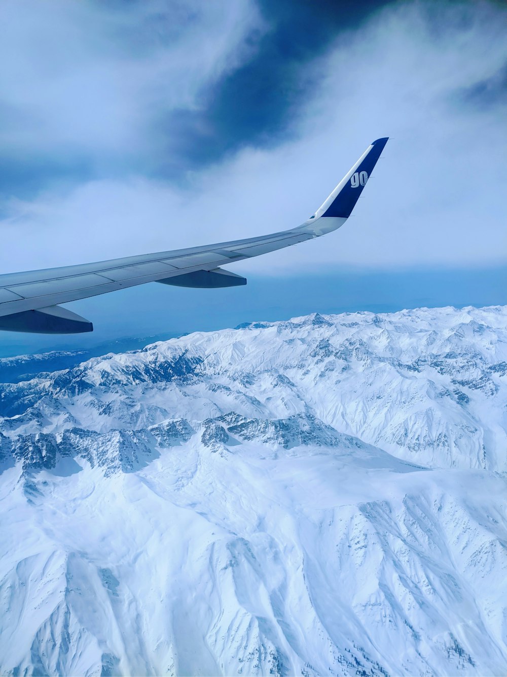 an airplane flying over a snowy mountain range