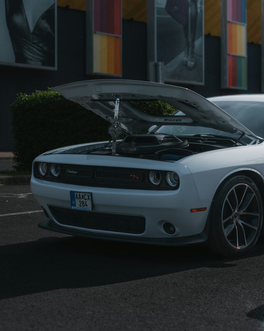 a white car with a hood open parked in a parking lot