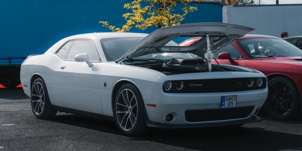 a white car with a hood open in a parking lot