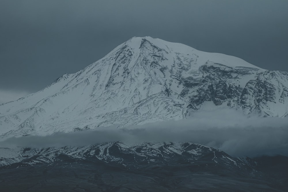 uma montanha coberta de neve com nuvens em primeiro plano