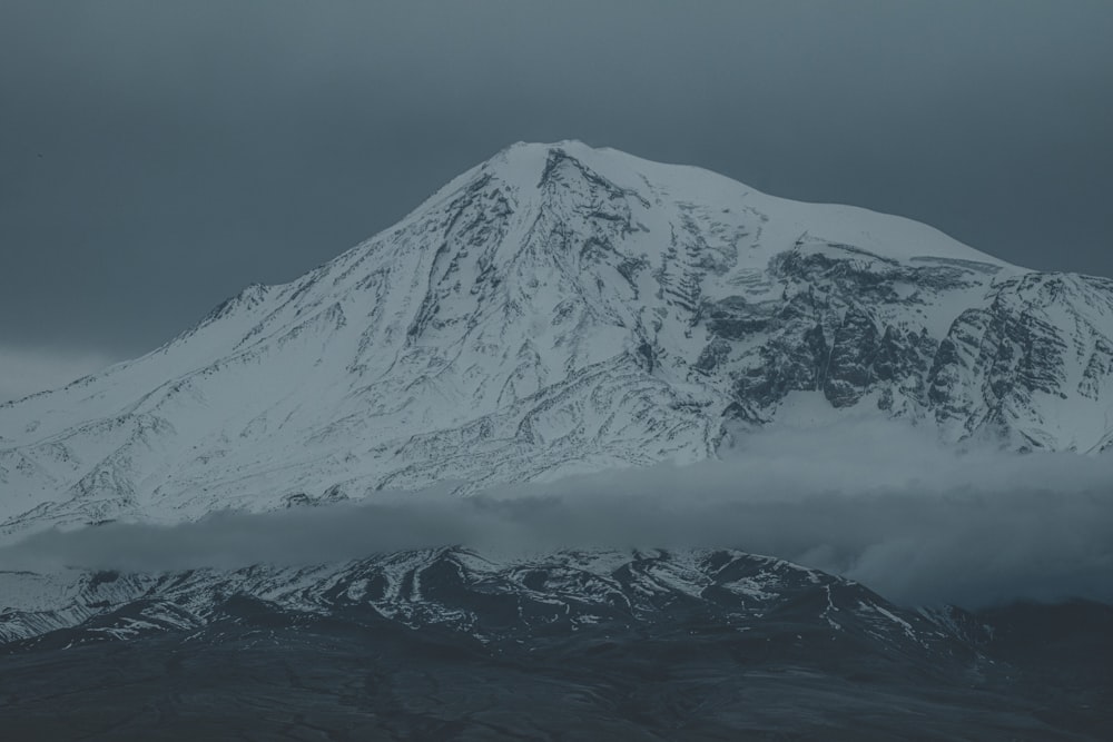 a snow covered mountain with clouds in the foreground