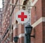 a red cross sign hanging from the side of a building