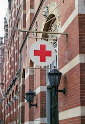 a red cross sign hanging from the side of a building