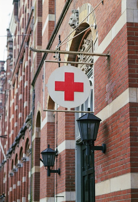 a red cross sign hanging from the side of a building