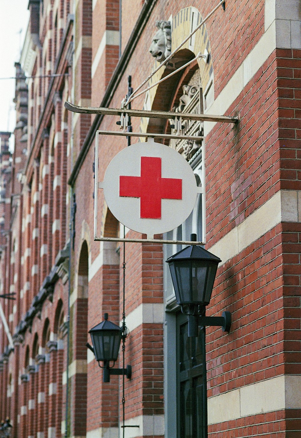 a red cross sign hanging from the side of a building