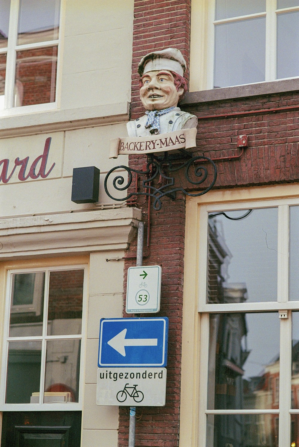 a street sign on a brick building with a statue of a man's head