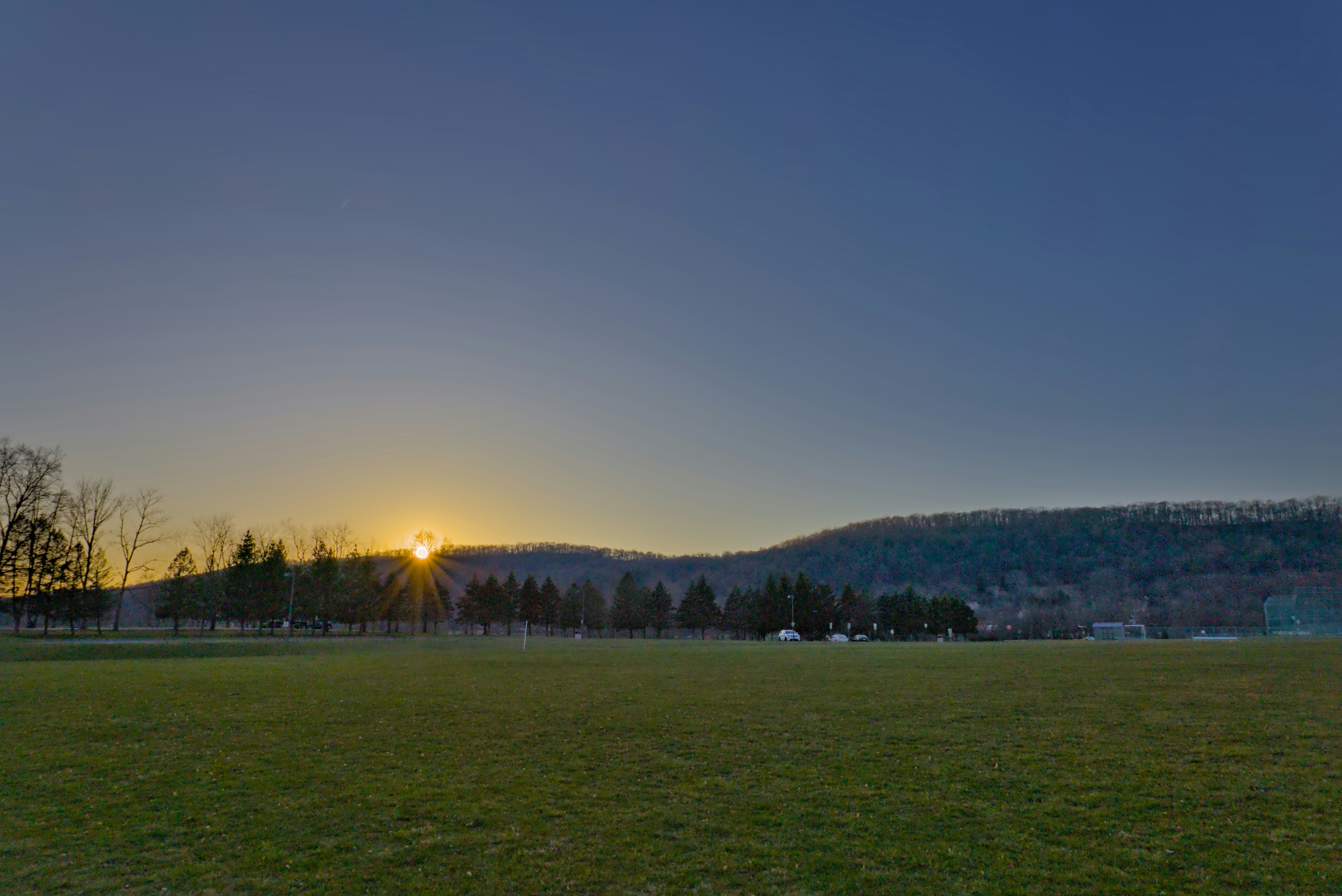 Die Sonne geht über einer Wiese unter