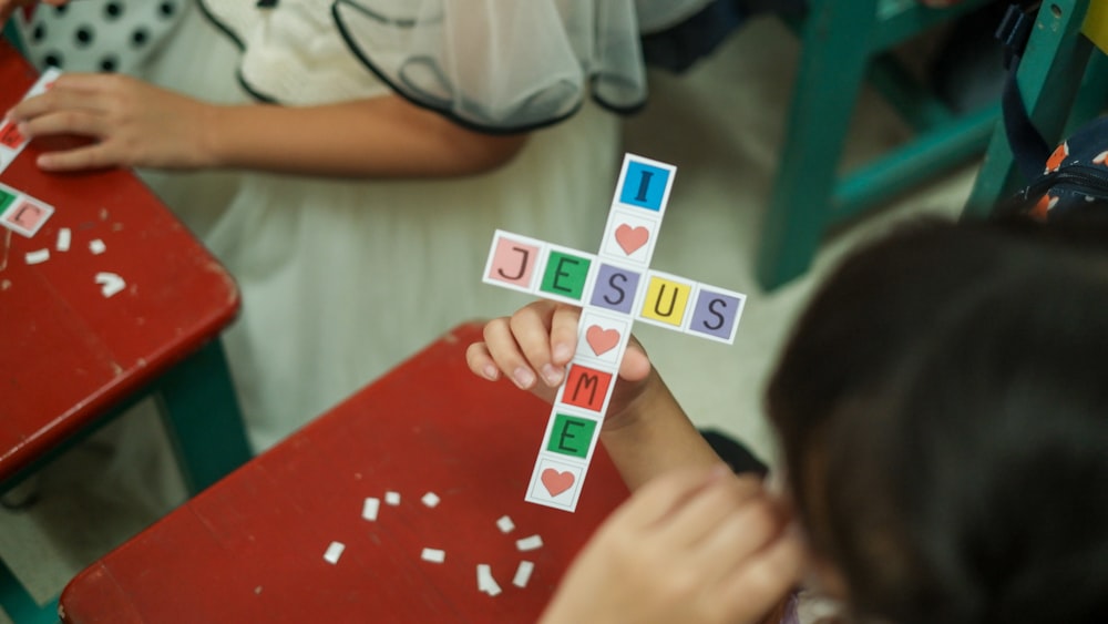 a young girl is holding a cross made of paper