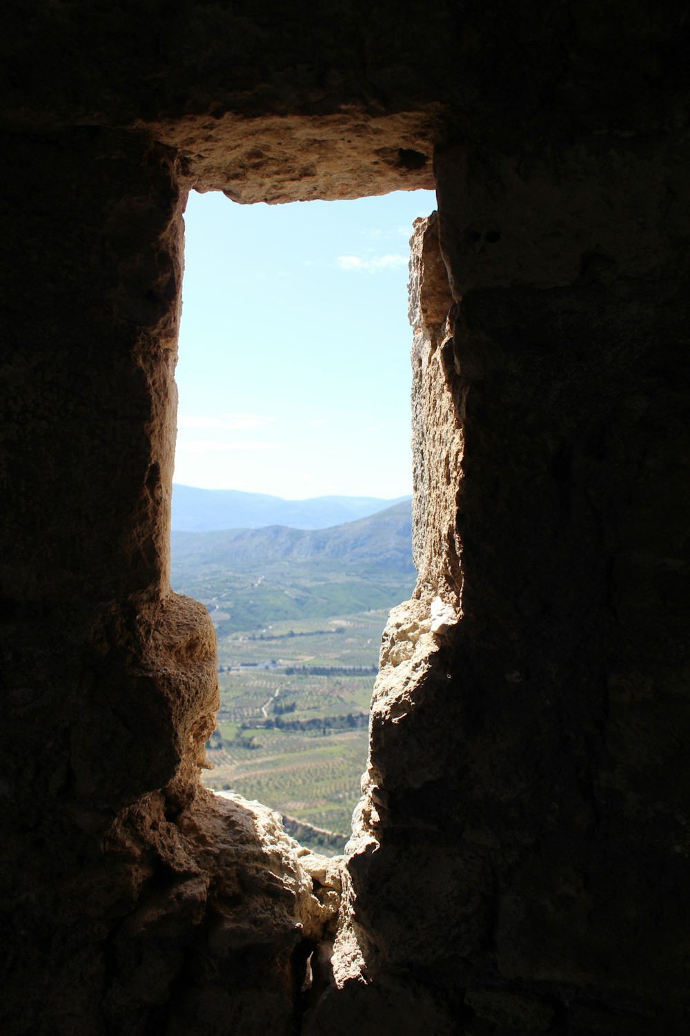 a window in a stone wall with a view of a valley