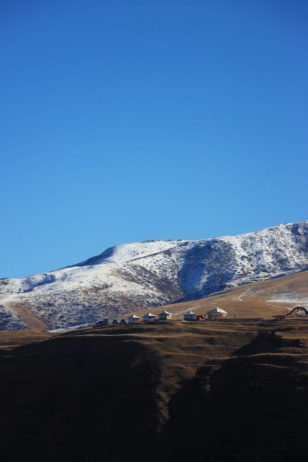 a snowy mountain with a few houses in the foreground