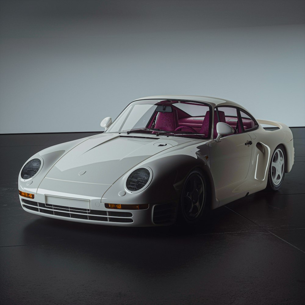 a white sports car parked on top of a black floor