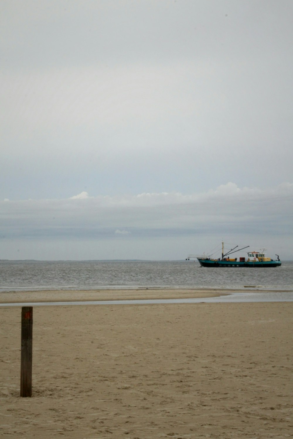 a boat is in the distance on the beach
