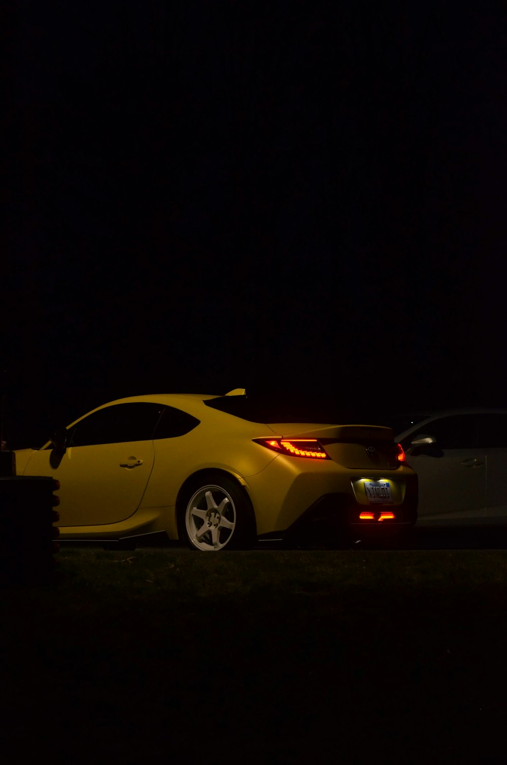a yellow sports car parked in the dark