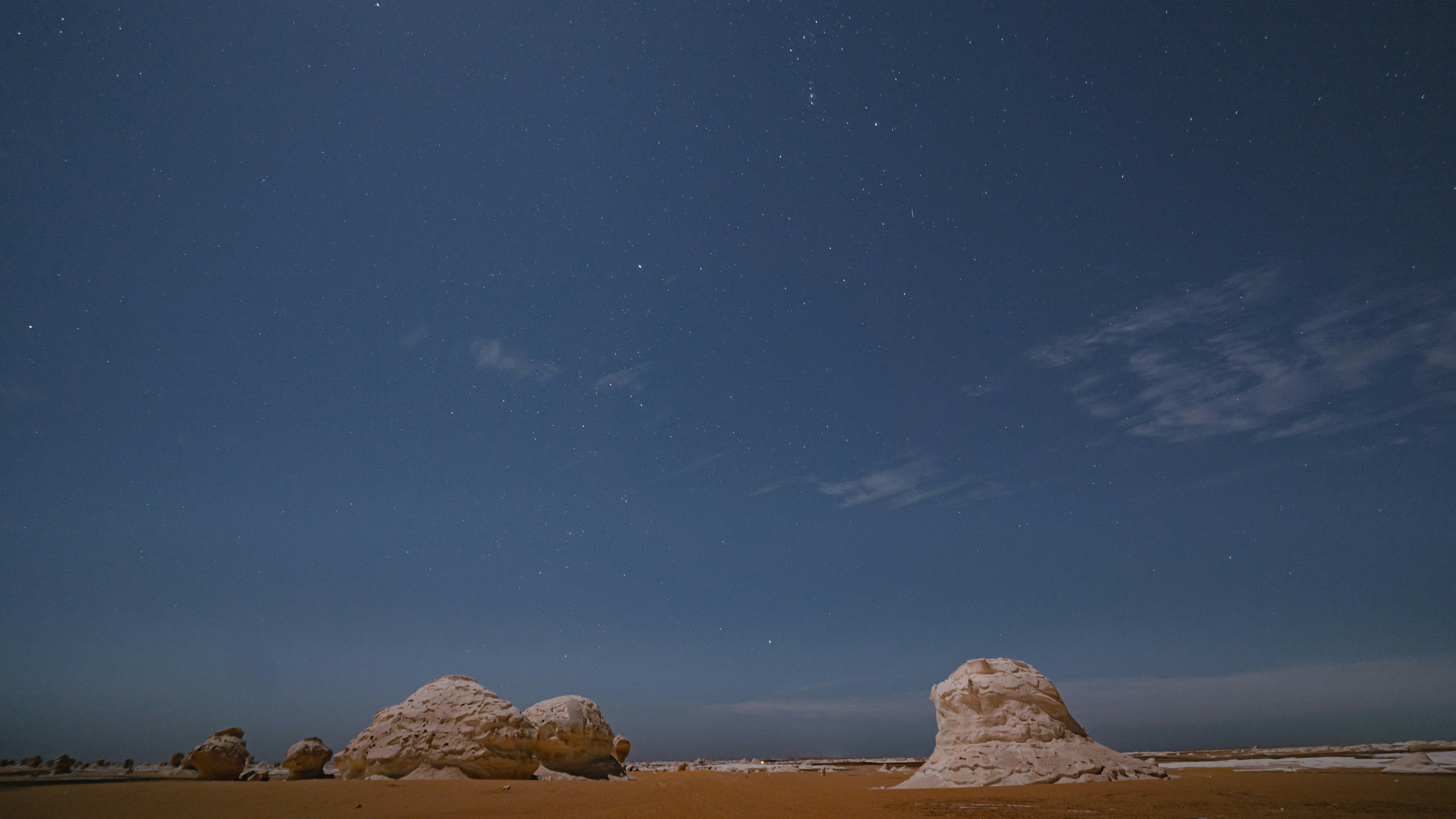 Un paisaje desértico con rocas y estrellas en el cielo