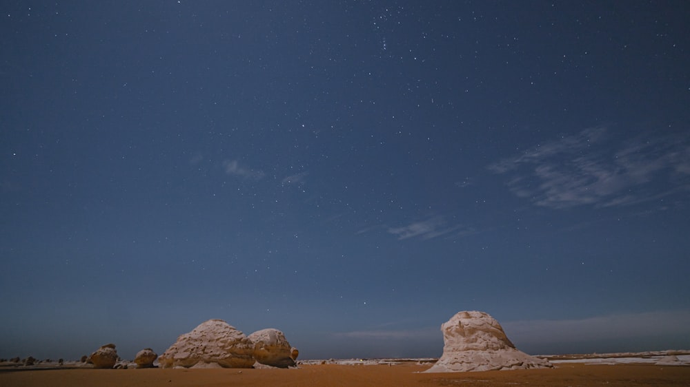 a desert landscape with rocks and stars in the sky