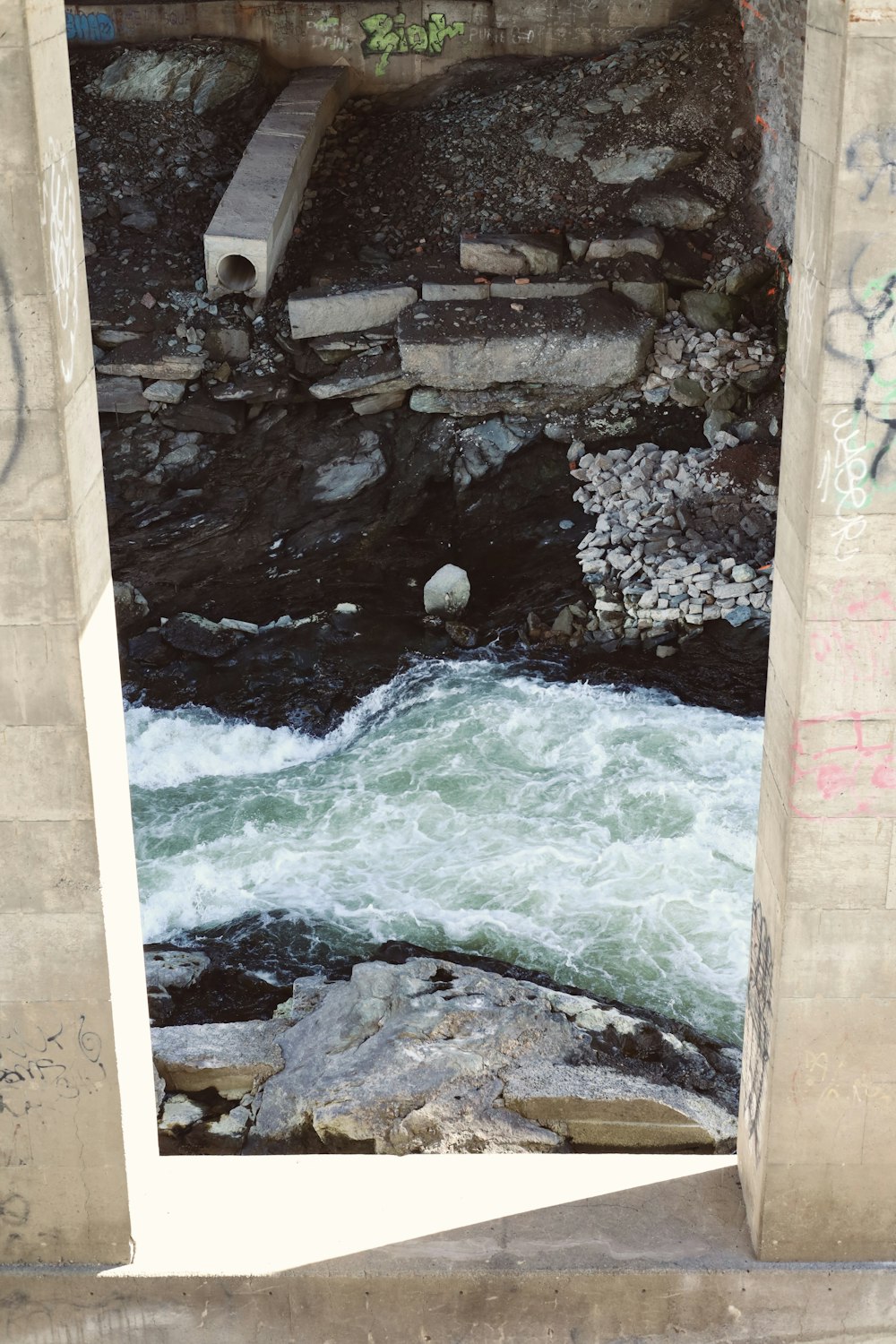 a river flowing under a bridge next to a stone wall