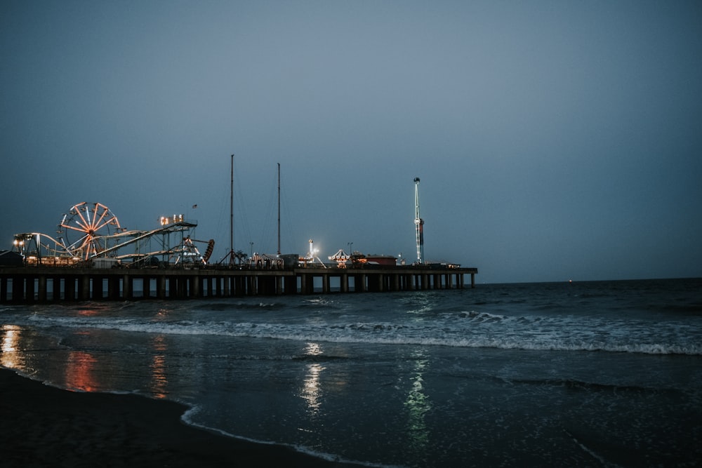 a pier with a ferris wheel and a ferris wheel in the distance