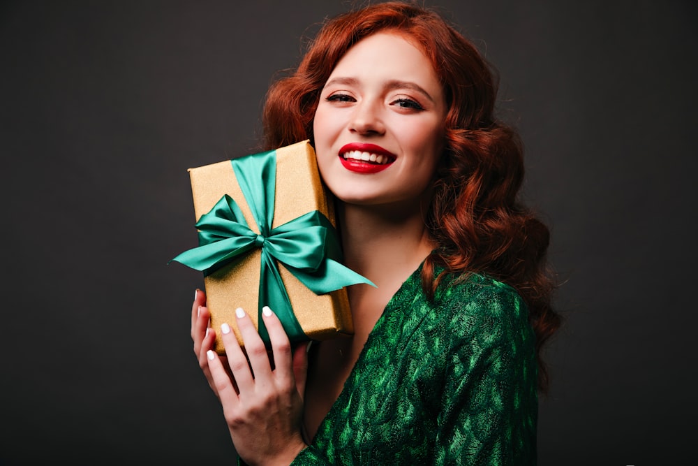 a woman holding a present box with a green bow