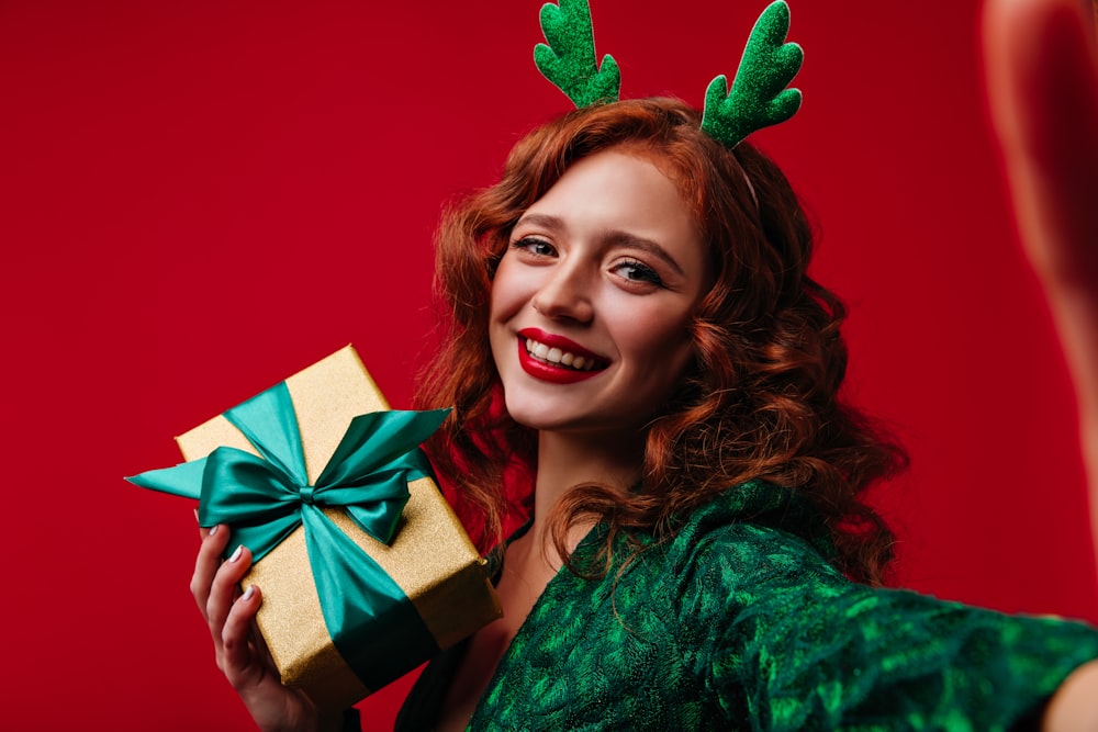 a woman wearing reindeer antlers holding a present