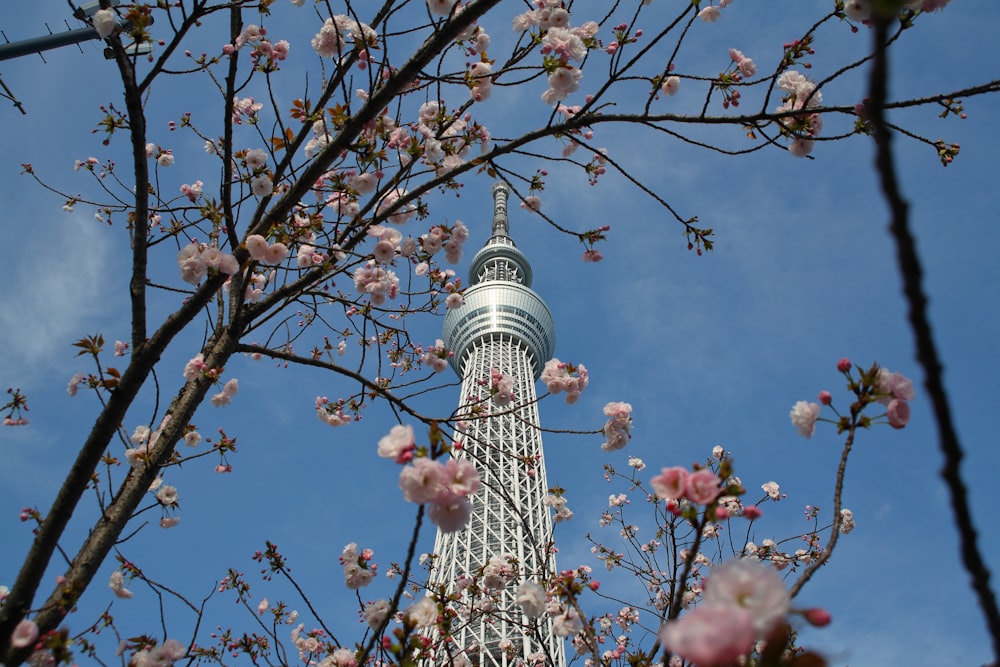uma torre muito alta com um monte de flores cor-de-rosa sobre ele