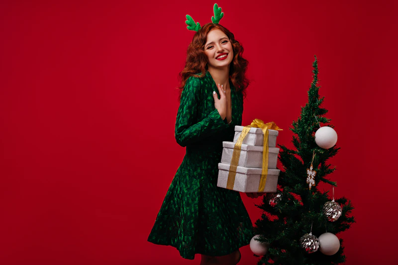 woman in green dress holding a gift near a Christmas tree